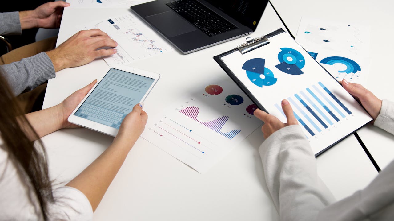 brand-01 Team analyzing financial charts and digital reports during a business meeting.