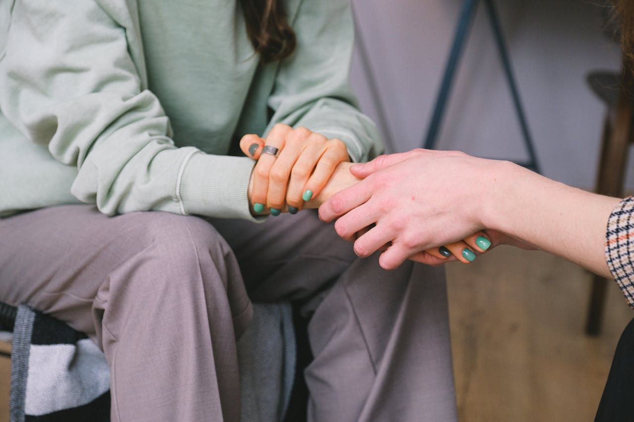 creative-01 Close-up of two people holding hands during a comforting therapy session.